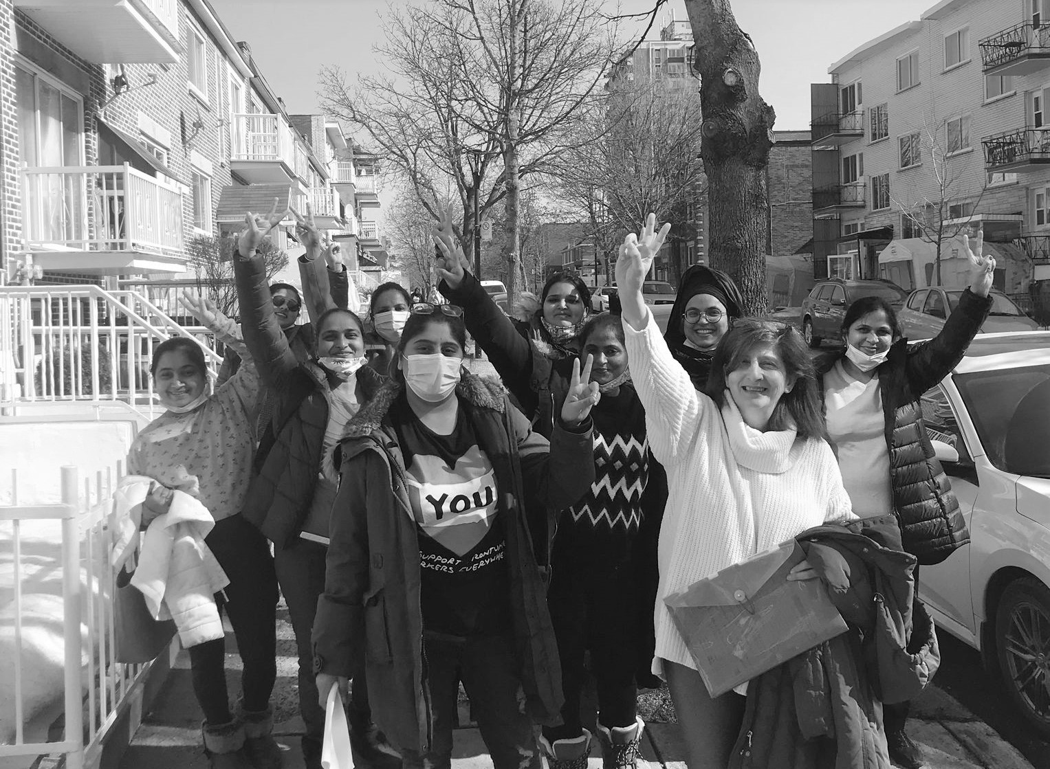 La cohorte de PAM 2022 prends une marche dans la rue à Parc-Extension. Plusieurs d'entre elles lèvent la main pour faire la signe de paix.